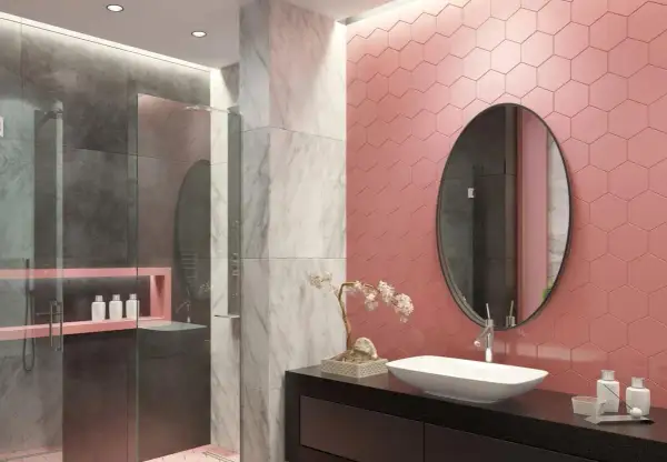 Bagno moderno con doccia, dove le piastrelle rosa a nido d'ape contrastano con il grigio e il marmo.