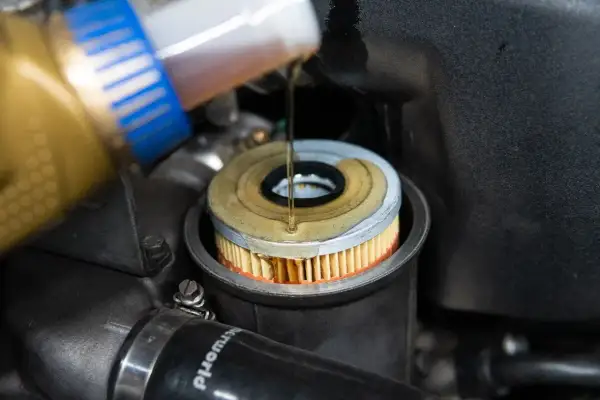 Öl wird in einen neuen Ölfilter gegossen, der in einem BMW E46 Motor sitzt.