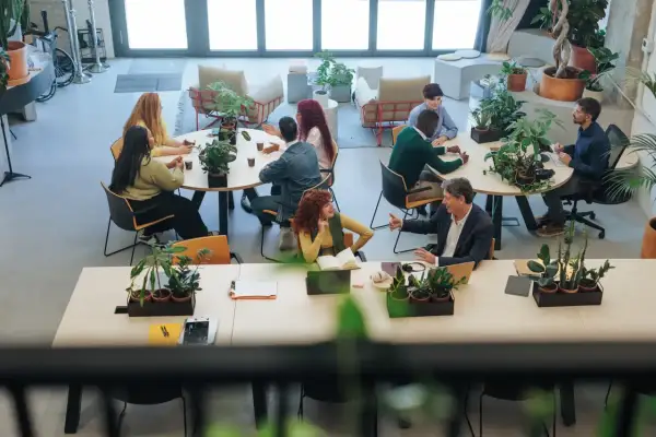 Ludzie pracują i rozmawiają w jasnej przestrzeni, która pokazuje, coworking co to.