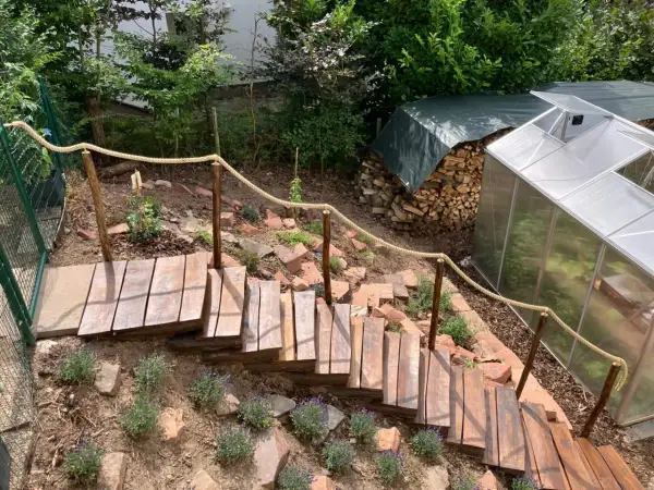 Eine **einfache Gartentreppe selber bauen** ist hier gelungen. Holzstufen mit Seilgeländer führen durch einen Hang mit Lavendel.
