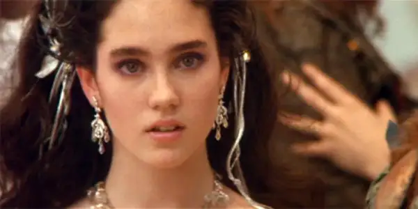 Jennifer Connelly w filmach, z burzą ciemnych włosów ozdobionych srebrnymi dodatkami i wyrazistym makijażem oczu.