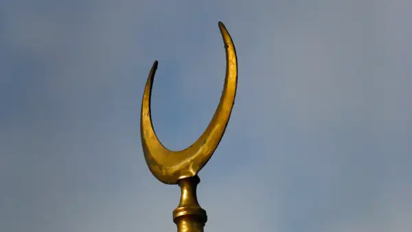 Złoty półksiężyc, symbol meczetu, na tle błękitnego nieba.