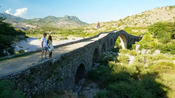 Pareja admira un puente de piedra histórico, un lugar perfecto para un viaje a Albania de 5 días.
