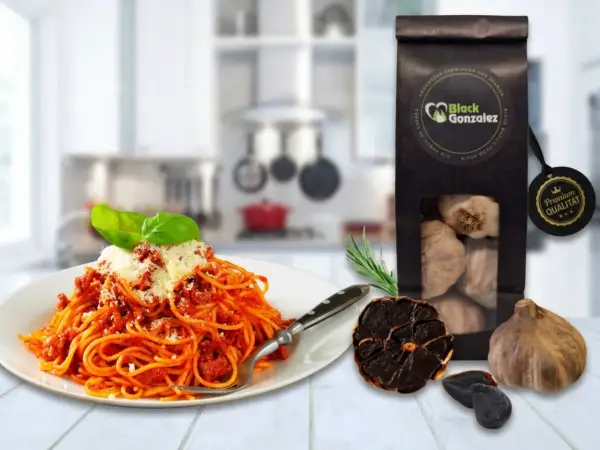 Spaghetti mit Tomatensoße, daneben eine Packung schwarzer Knoblauch und ganze Knoblauchzehen. Perfekt für schwarzer Knoblauch Rezepte.