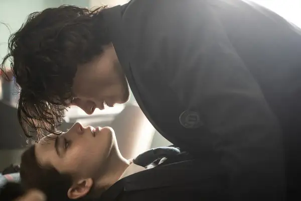 Młody mężczyzna pochyla się nad dziewczyną, jakby był rzeźbiarzem łez, próbując uchwycić ulotne emocje w jej spojrzeniu.