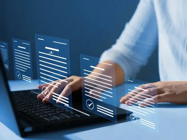 Ręce nad klawiaturą laptopa, wirtualne dokumenty unoszą się w powietrzu, symbolizując cyfrowe przetwarzanie wniosków, np. zaświadczenie o zameldowaniu.