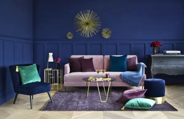 Elegancki salon z granatową ścianą, różową kanapą i złotymi dodatkami. Inspiracje dla odważnych.