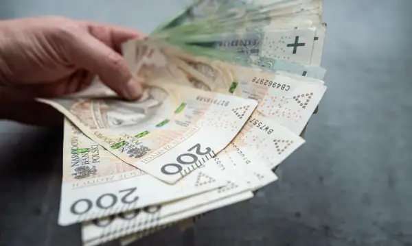 Dłoń trzyma plik banknotów 200 zł. Czy współwłaściciel konta może wypłacić pieniądze po śmierci właściciela?