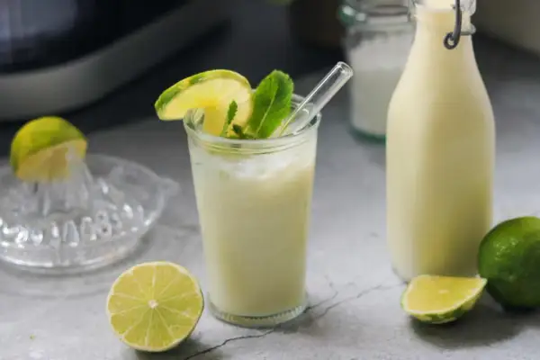 Erfrischende brasilianische Limonade mit Limettenscheiben und Minze, daneben eine Flasche und frische Limetten.
