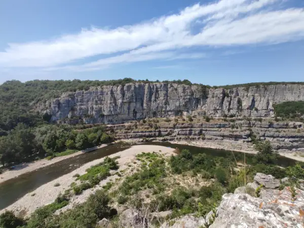 Un cirque de gens, des kayakistes profitent de la rivière au pied d'une falaise imposante.