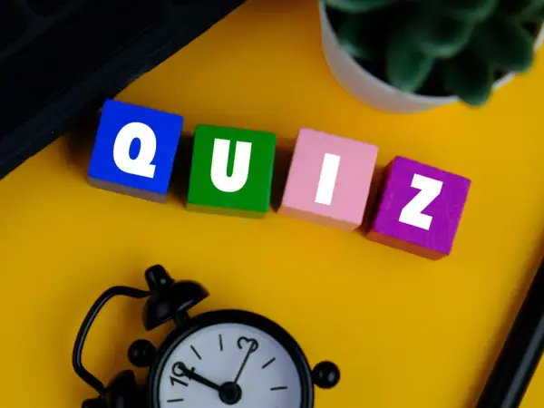 Kolorowe klocki z literami tworzą słowo QUIZ. Zegar i roślina sugerują, że czas sprawdzić swoją znajomość!