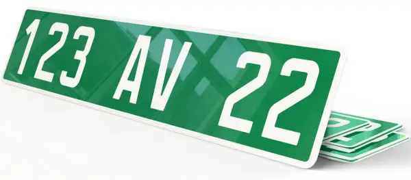 Plaque verte voiture avec "123 AV 22" en blanc. D'autres plaques similaires sont empilées en dessous.