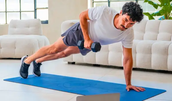 Uomo in posizione di plank con manubrio, esercizio per come migliorare la postura. Allenamento a casa.