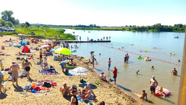 Ludzie odpoczywają na piaszczystej plaży nad rzeką, w krainie dolnej Wisły. Kąpiel, opalanie i relaks w upalny dzień.