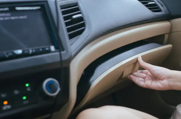Mano apre il cassetto portaoggetti per recuperare i documenti obbligatori in auto.