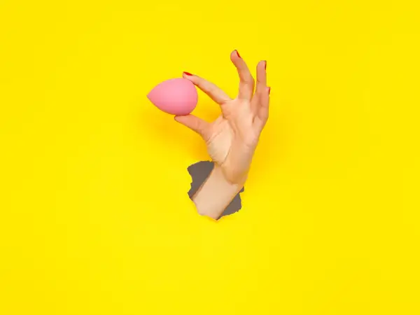 Mano con beauty blender rosa, un modo semplice per capire come pulire le beauty blender.