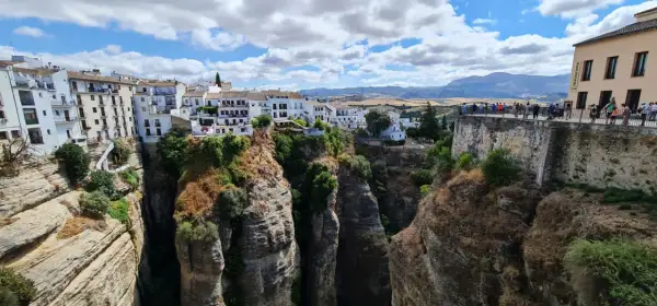 El mirador La Hoya del Tajo ofrece vistas espectaculares de casas blancas al borde de un profundo tajo, con gente admirando el paisaje.