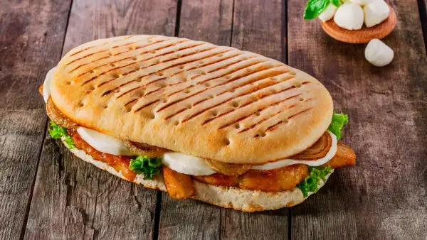 Ein gegrilltes Panini mit Hähnchen, Mozzarella, Salat und karamellisierten Zwiebeln. Ein leckeres panini rezept für jeden Tag.