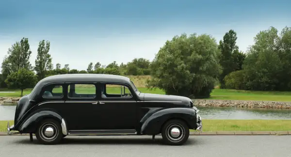 En svart, klassisk Volvo står parkerad vid en sjö. Denna gamla skönhet är en riktig sugga bil, perfekt för en tidlös resa.