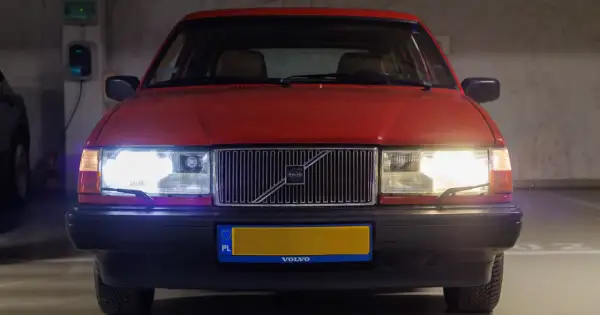 Czerwone Volvo z włączonymi światłami. Czy ledy mogą się zapalić? Tak, te świecą jasno, oświetlając parking.