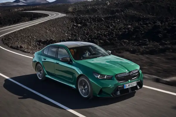 Zielony BMW M5 2025 pędzi po krętej drodze wśród wulkanicznych krajobrazów.
