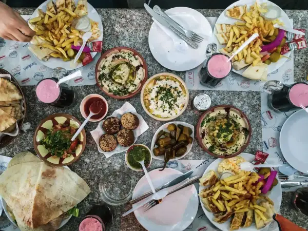 Obfity posiłek w Jordanii: hummus, falafel, frytki, sałatka i napoje. Ceny jedzenia w Jordanii są przystępne.