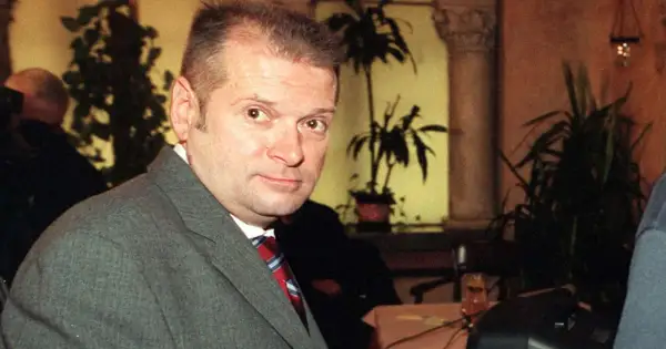 Rutkowski kiedys, w szarym garniturze i czerwonym krawacie, z uwagą patrzy w obiektyw.