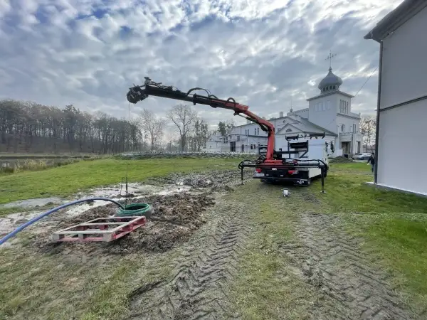 Dźwig z HDS pracuje przy studni, zapewniając własne ujęcie wody dla zabytkowego budynku.