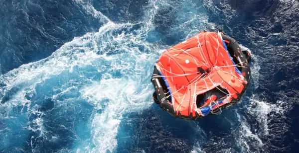 Una zattera di salvataggio arancione galleggia in un mare agitato. Il suo significato è speranza e sopravvivenza.