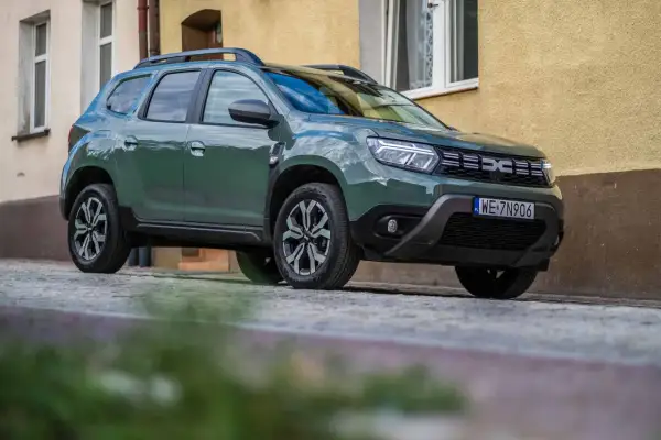 Zielony Dacia Duster na brukowanej ulicy. Wiele pozytywnych dacia duster opinie potwierdza jego wszechstronność.