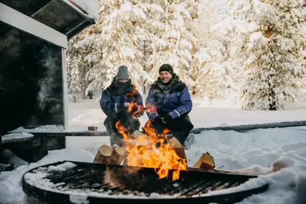 Couple réchauffé au feu de bois en Laponie. Idéal pour savoir quand partir en Laponie pour une expérience hivernale magique.