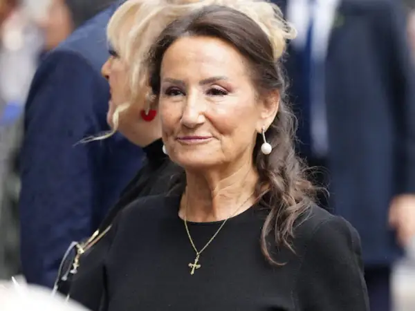 Paloma Rocasolano, con pendientes de perla y un collar con cruz, sonríe con elegancia.