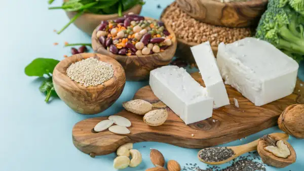 Vielfalt an vegetarischen Proteinquellen: Quinoa, Hülsenfrüchte, Tofu, Nüsse, Samen und Brokkoli.