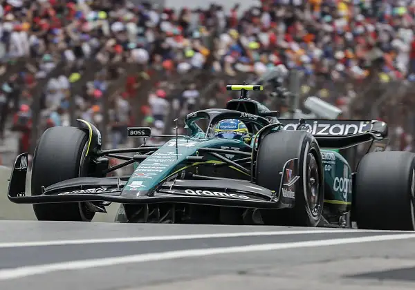 Coche de Fórmula 1 verde y negro en pista, con público al fondo. El piloto, con casco azul, busca ser libres 2.
