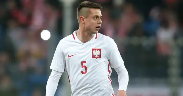 Piłkarz Borysiuk w białej koszulce z numerem 5 i godłem Polski.
