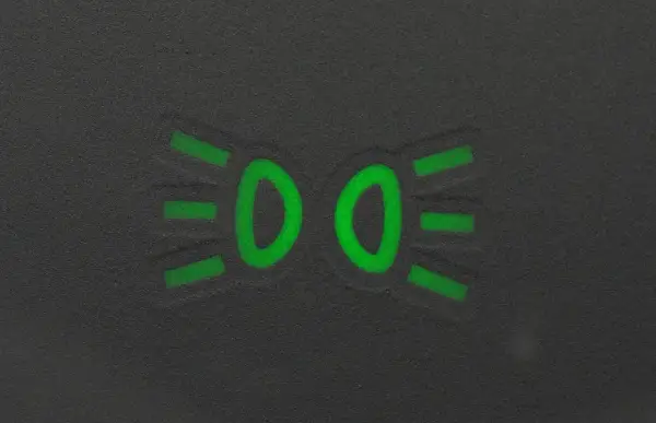 Zielony symbol świateł mijania na ciemnym tle.