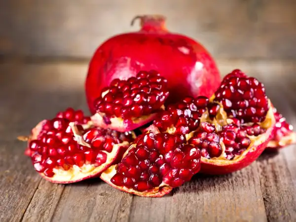 Saftige Granatapfelkerne auf Holz. Die Frucht, woher kommt der Granatapfel, stammt ursprünglich aus Persien und dem Nahen Osten.