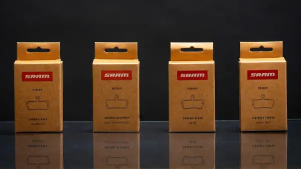 Cajas de SRAM mostrando distintos tipos de pastillas de freno: orgánicas (gris, aluminio, negra) y sinterizadas de cobre.