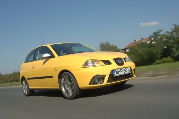 Żółty Seat Ibiza 3 w ruchu, widoczne przednie światła i żarówki.