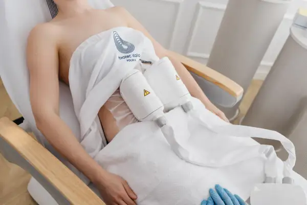 Kobieta poddana zabiegom modelującym sylwetkę, z aplikatorami na brzuchu.