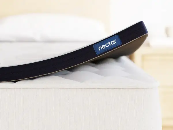 A Nectar mattress topper is shown. While toppers can improve comfort, it's worth considering if a mattress topper can cause back pain if it's too soft or firm for your needs.