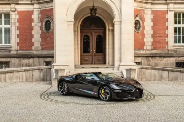 Czarny Bugatti przed pałacem. To auto, z jakiego kraju jest Bugatti, symbolizuje francuską elegancję i moc.
