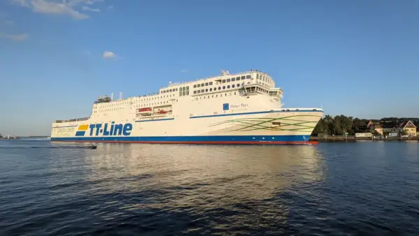 Duży biały prom TT-Line "Peter Pan" płynie po wodzie przy słonecznej pogodzie.