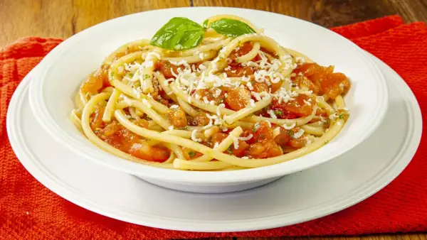 Un piatto invitante di pasta alla carrettiera, con pomodoro fresco, basilico e formaggio grattugiato.