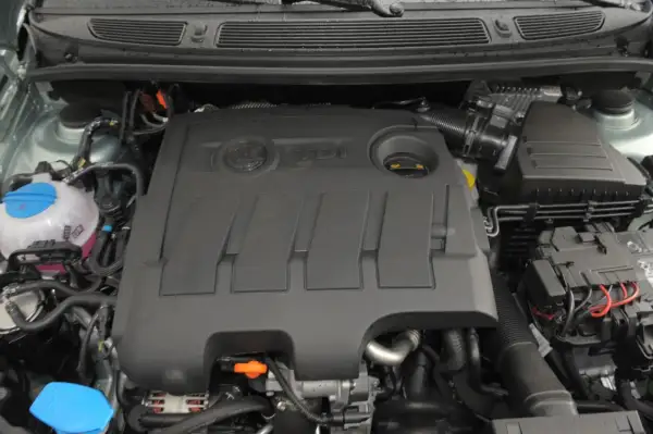 Silnik 1.6 TDI z widocznym logo TDI na pokrywie. Widać zbiornik płynu chłodniczego i elementy układu dolotowego.