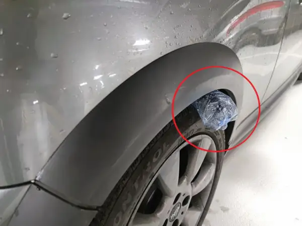 Plastikowa butelka utknęła w nadkole samochodu, tworząc nietypową ozdobę.