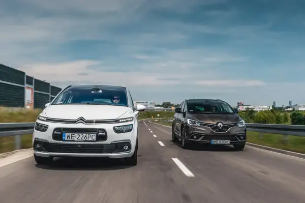 Biały Citroën C4 Grand Picasso i brązowy Renault Scenic jadą obok siebie drogą.