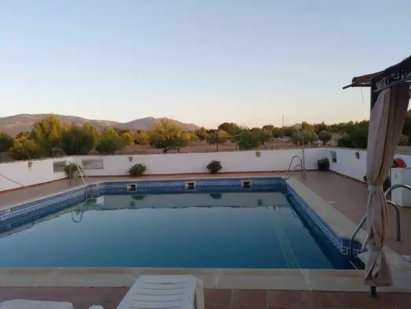 Piscina con vistas a montañas y vegetación bajo un cielo despejado.