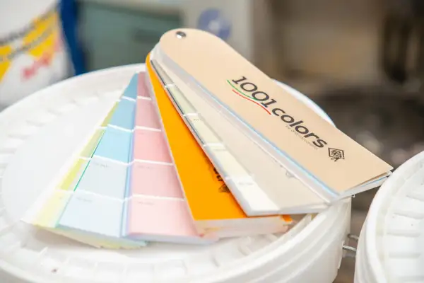 Ventaglio di campioni di colori per la tintometria, con tonalità pastello e vivaci, su secchi bianchi.