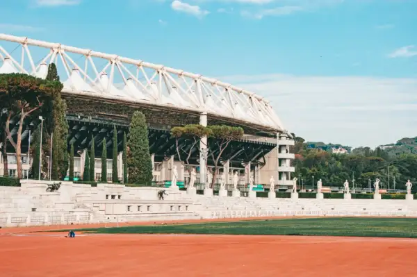 Stadion w Rzymie z rzędami rzeźb i zielenią.
